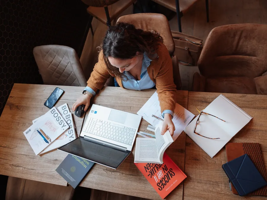 Bureau van bovenaf met boeken, notities en laptop