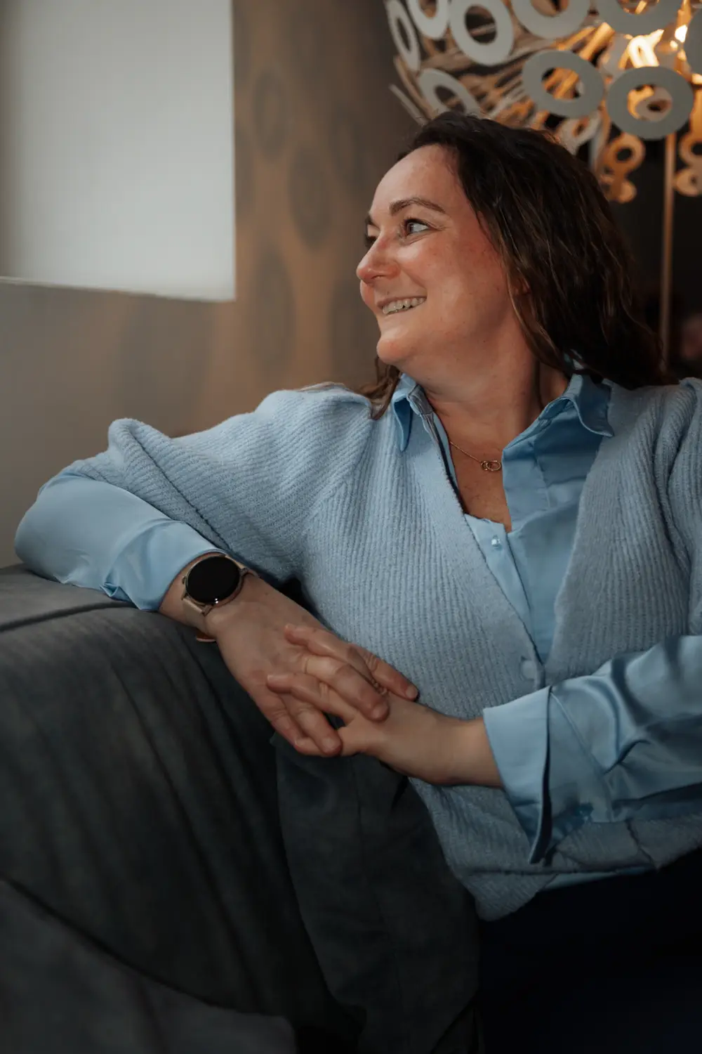 Annelies Neven zit ontspannen op een zetel en kijkt luisterend opzij