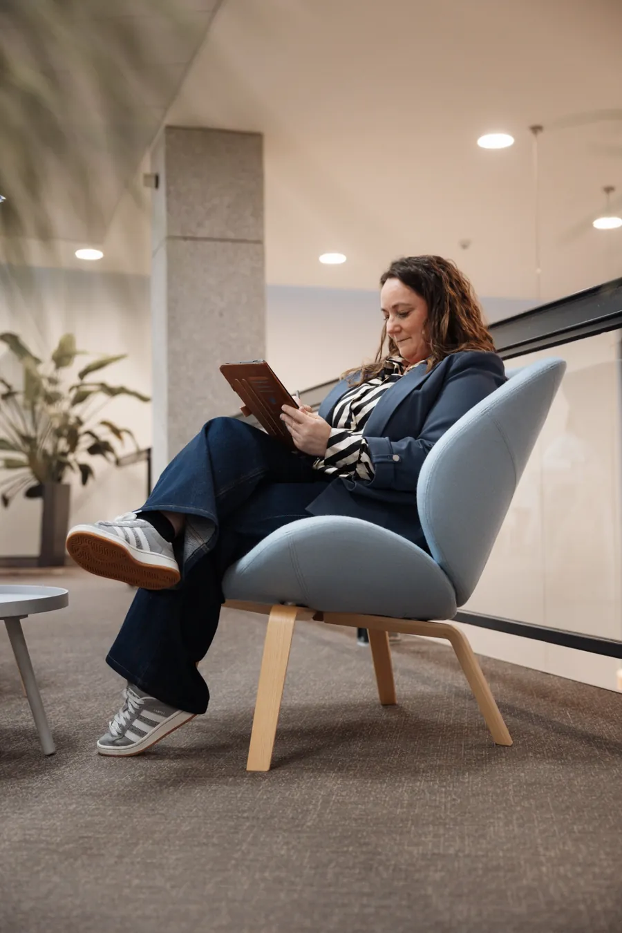 Annelies leest op een tablet in een zetel, ontspannen maar geconcentreerd