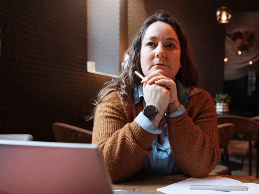 Zaakvoerder aan tafel, denkend, met laptop en notities