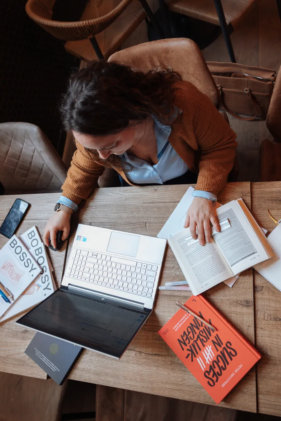 Bovenaanzicht van Annelies aan een werktafel met laptop, boeken en notities